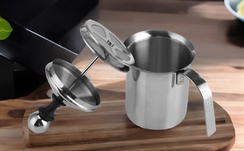 Making a creamy latte Using a handheld milk frother In kitchen 
