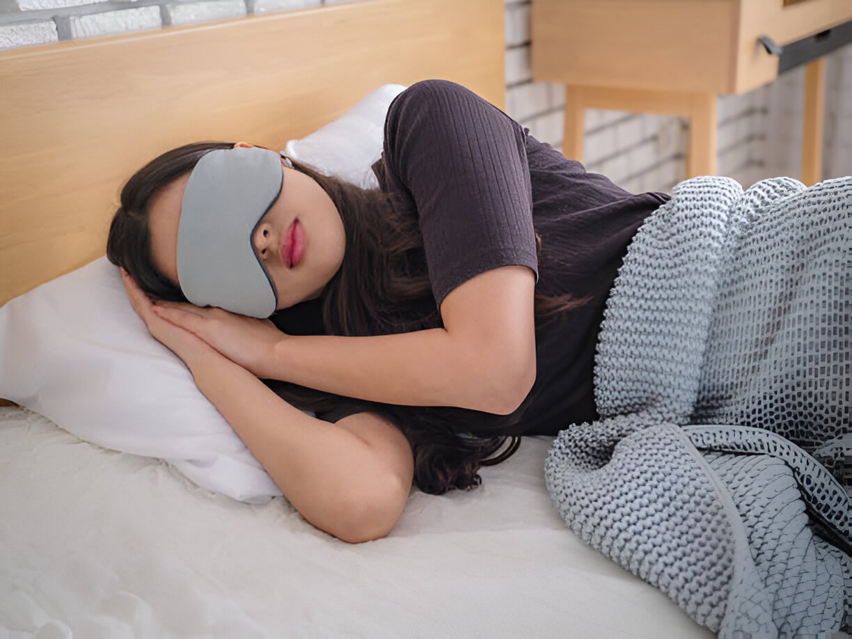 A woman wearing a MUSICOZY sleep headband is soundly asleep. Sleeping headphones